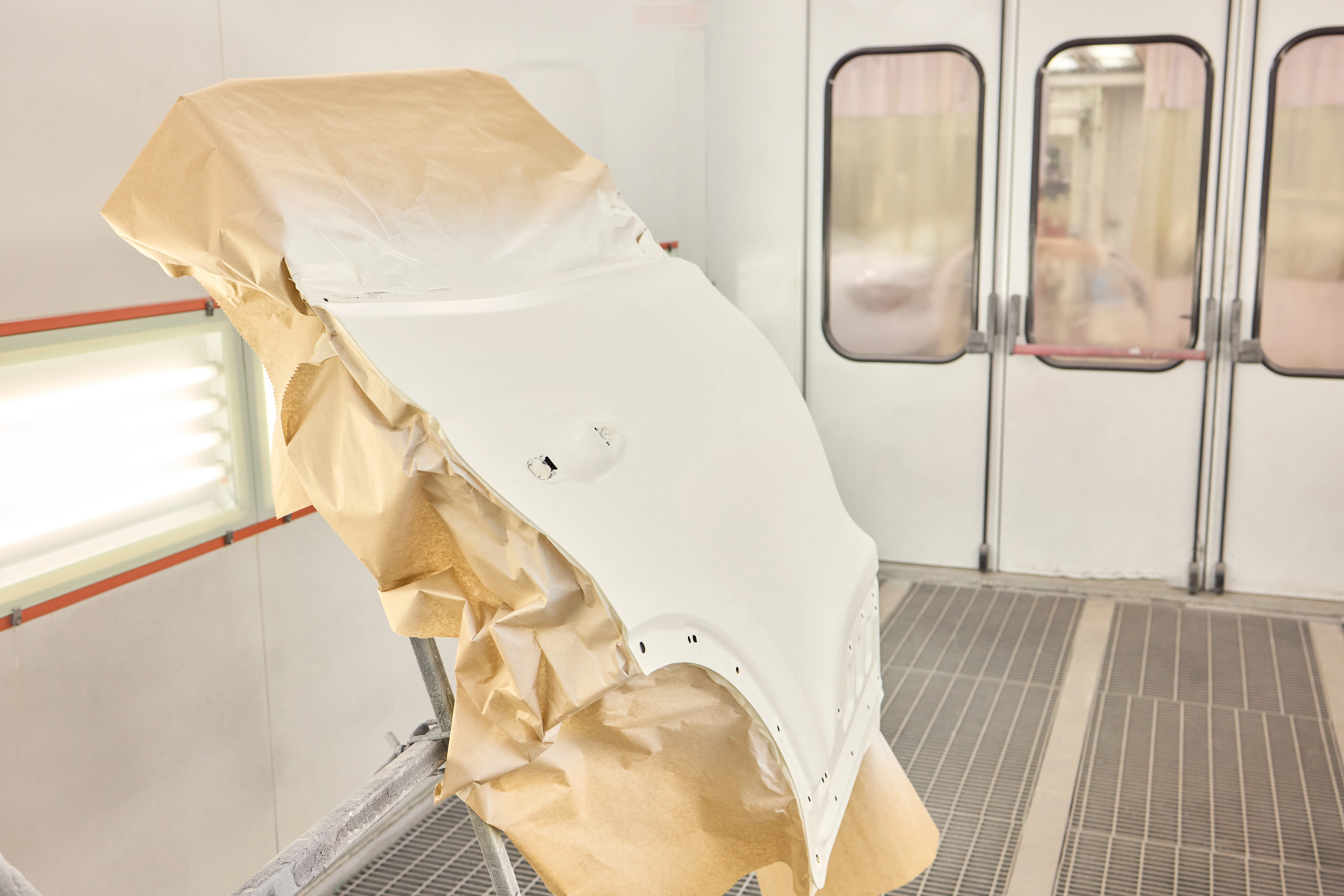Vehicle panel masked and prepared inside a professional spray booth